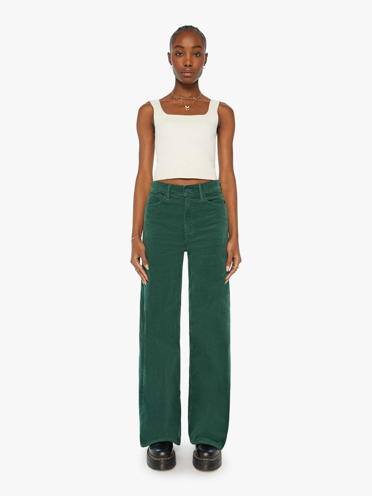 Front view of a woman in dark green corduroy wide-leg jeans feature a zip fly, low-set back pockets, high-rise with a slightly dropped crotch and a slouchier fit.