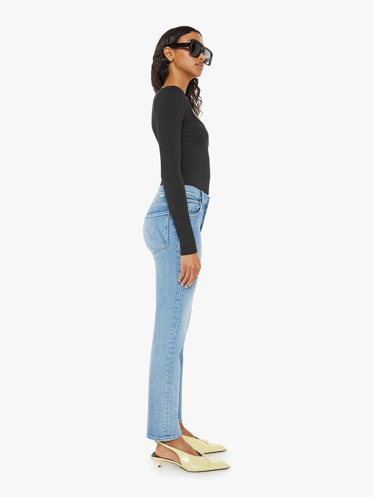 Side view of a woman in a mid blue slim straight-leg was adopted from our men’s line and features a mid rise, button fly, low-set back pockets and a clean hem. 