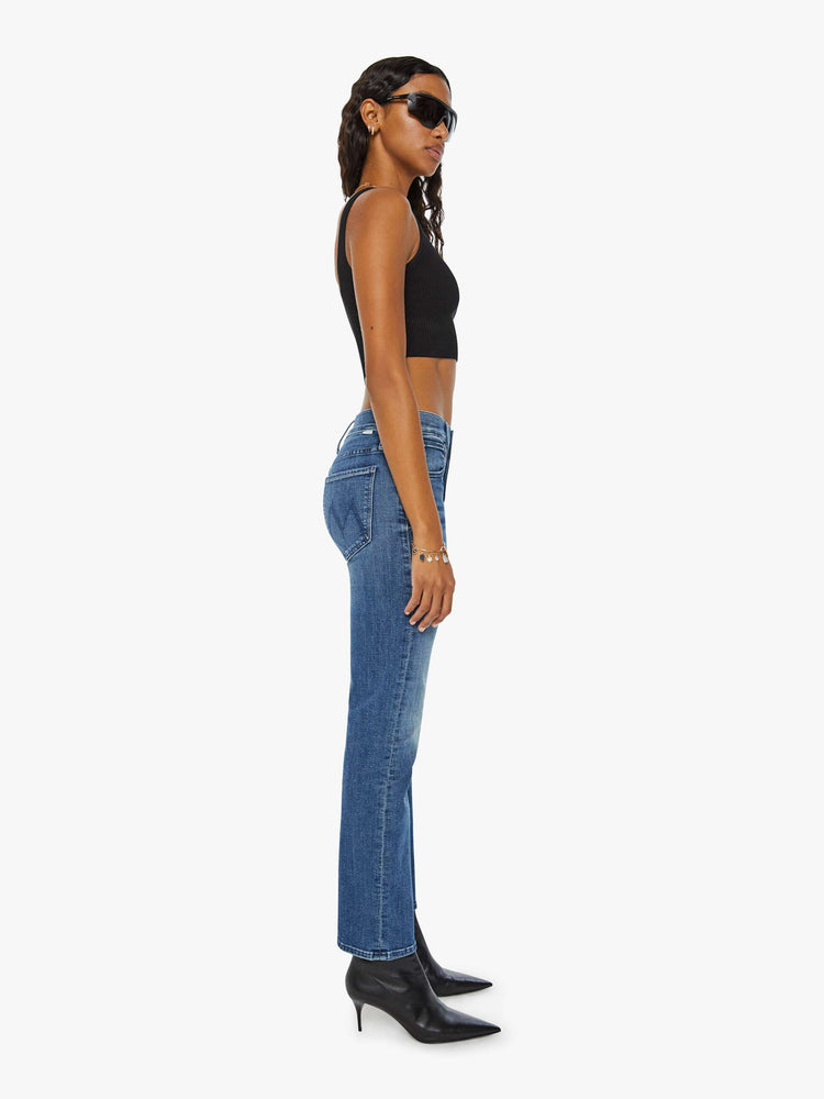 Side view of a woman in medium blue slim straight-leg (adopted from our men’s line) featuring a mid rise, button fly, low-set back pockets and a clean hem.