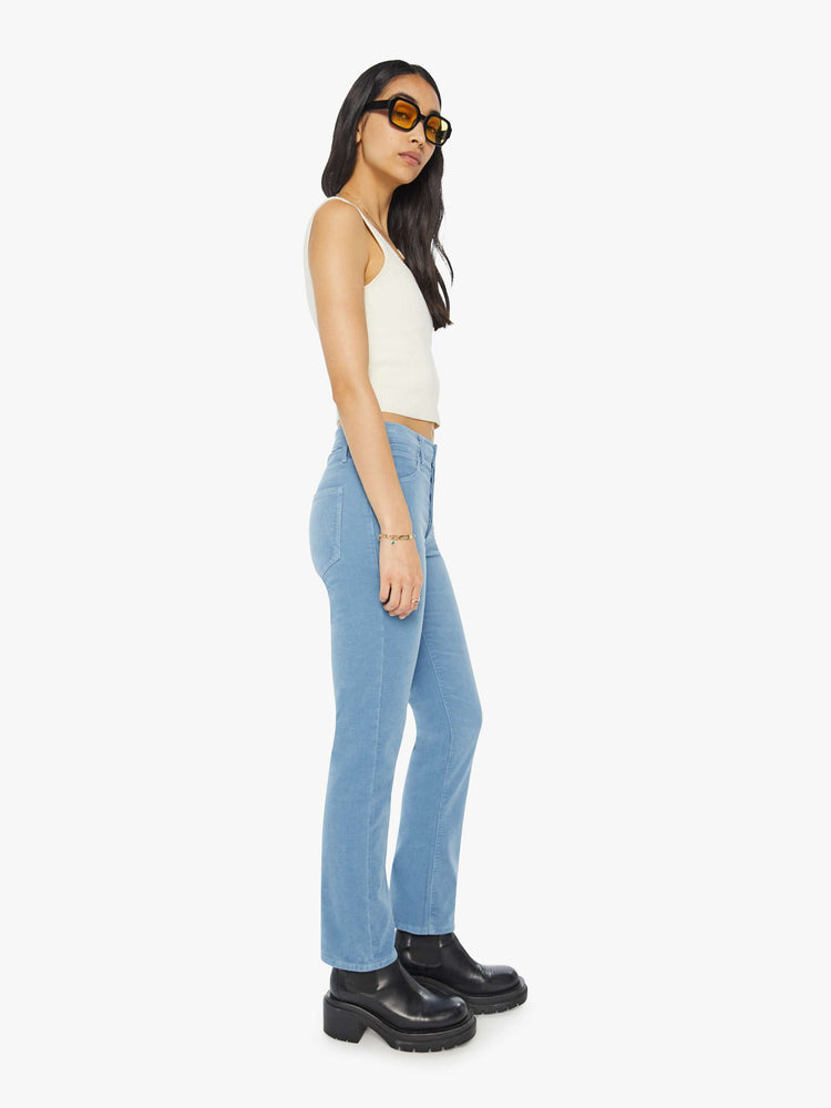 Side view of a woman in light blue corduroy slim straight-leg pants that feature a mid rise, button fly, low-set back pockets and a clean hem.