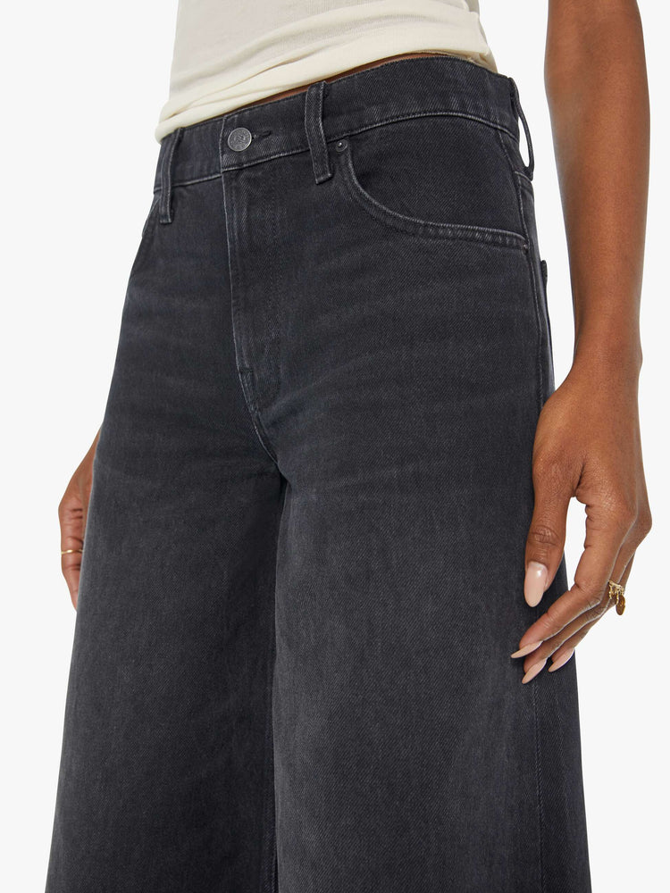 Waist view of a woman in faded black slouchy jeans are meant to sit lower on the hips, and feature a loose, full leg and a long 32-inch inseam.