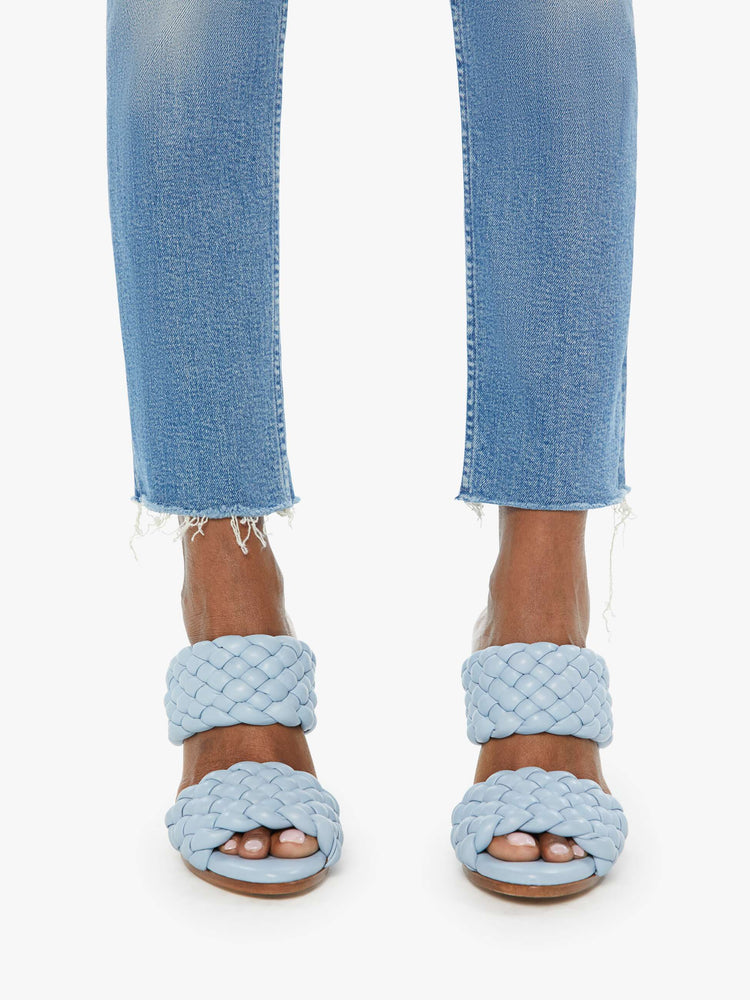 Hem view of a woman in a light blue high-rise jean with a straight leg, button fly and a frayed hem.