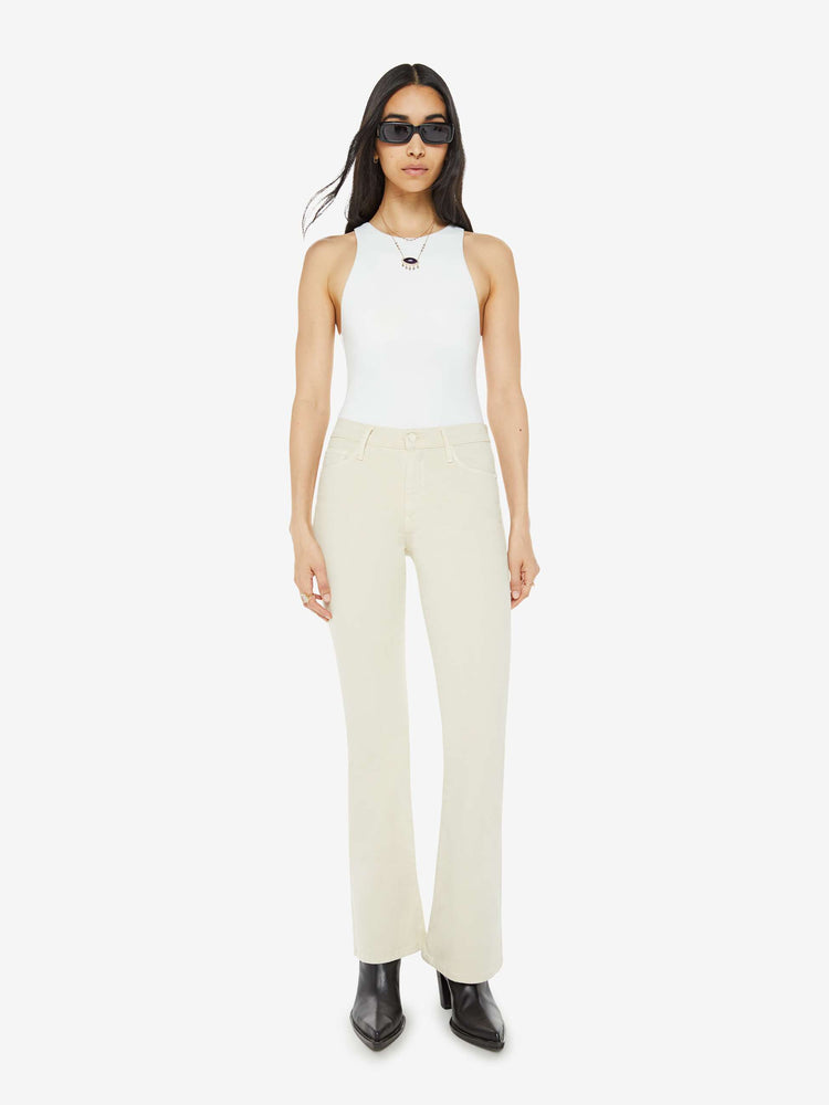 Front view of a woman in an off white color flare jean has a mid rise with a 32-inch inseam and a clean hem.