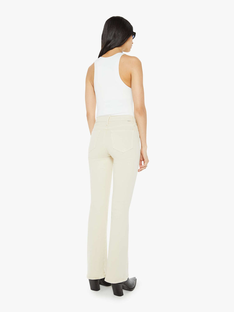 Back view of a woman in an off white color flare jean has a mid rise with a 32-inch inseam and a clean hem.