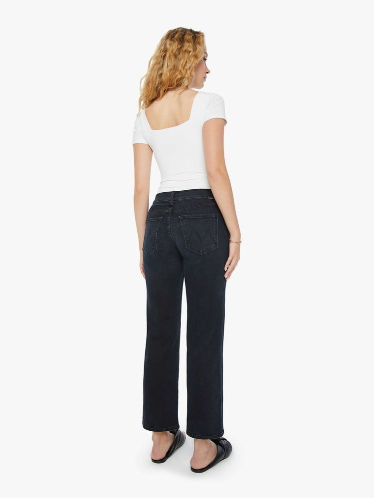 Back view of a woman in a dark denim mid-rise jean with a wide straight leg, zip fly and clean ankle-length inseam.