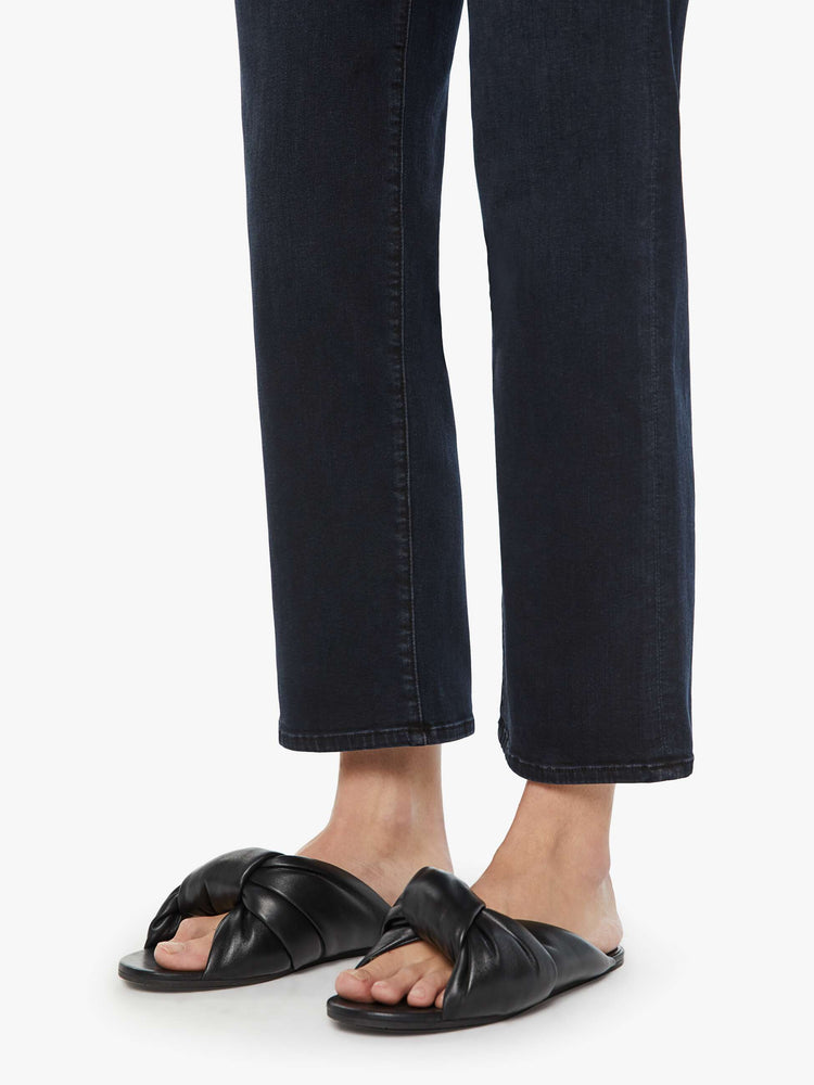 Close up hem view of a woman in a dark denim mid-rise jean with a wide straight leg, zip fly and clean ankle-length inseam.