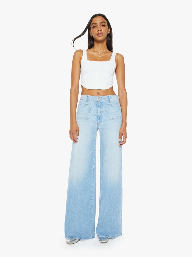 Front view of a woman in a light blue wash wide leg pants with a high rise, long 32-inch inseam and patch pockets. 