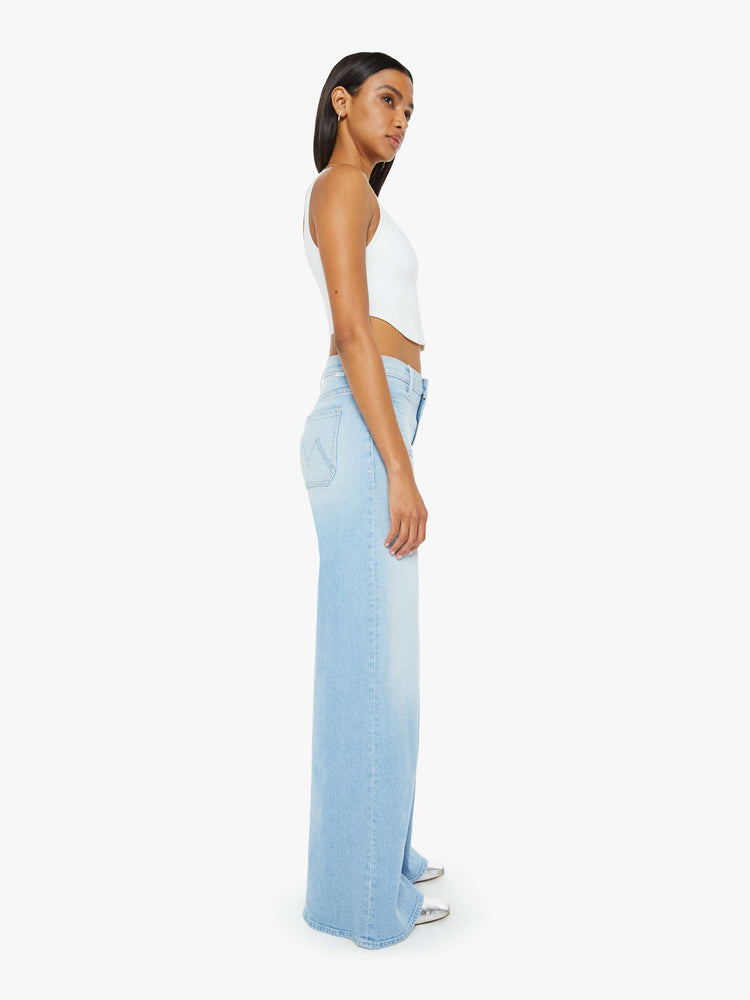 Side view of a woman in a light blue wash wide leg pants with a high rise, long 32-inch inseam and patch pockets. 