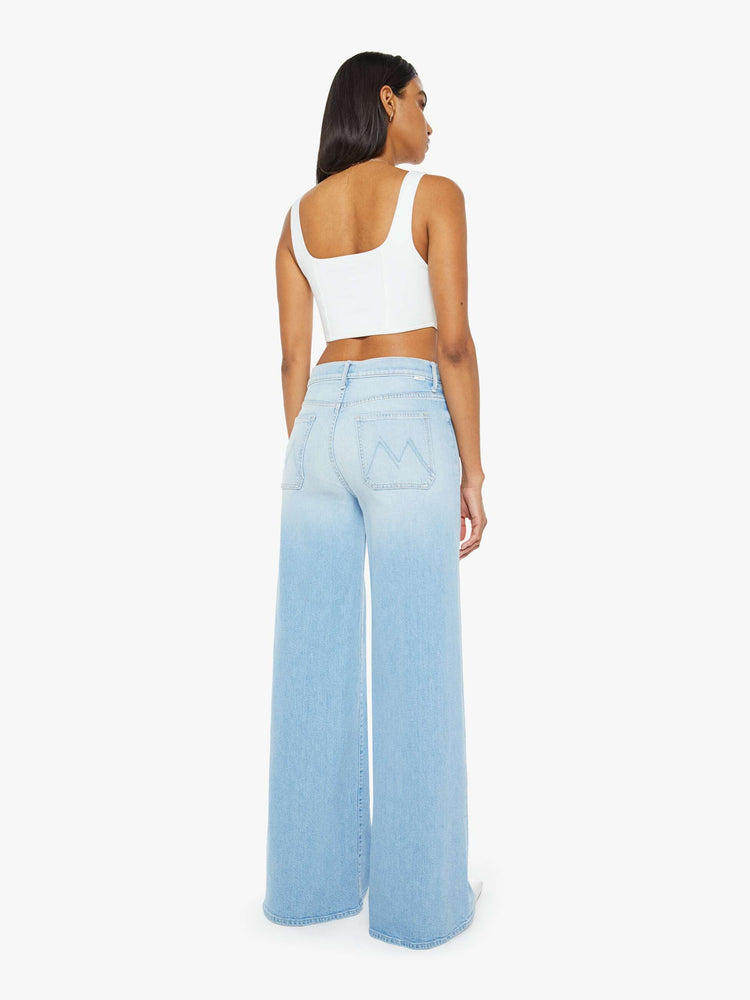 Back view of a woman in a light blue wash wide leg pants with a high rise, long 32-inch inseam and patch pockets. 