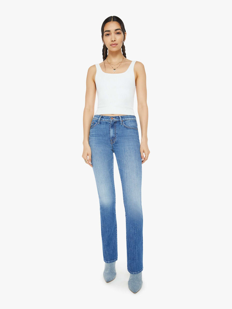 Front view of a woman in a high-waisted bootcut has a 32-inch inseam and a clean hem in a mid blue wash.