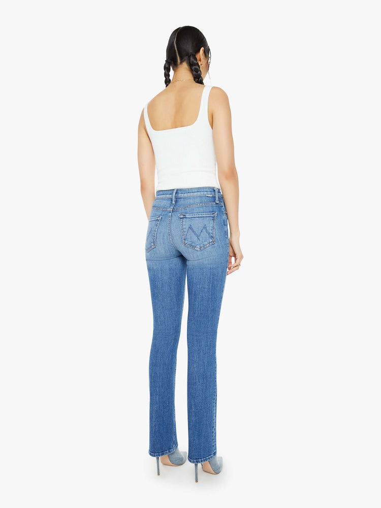 Back view of a woman in a high-waisted bootcut has a 32-inch inseam and a clean hem in a mid blue wash.