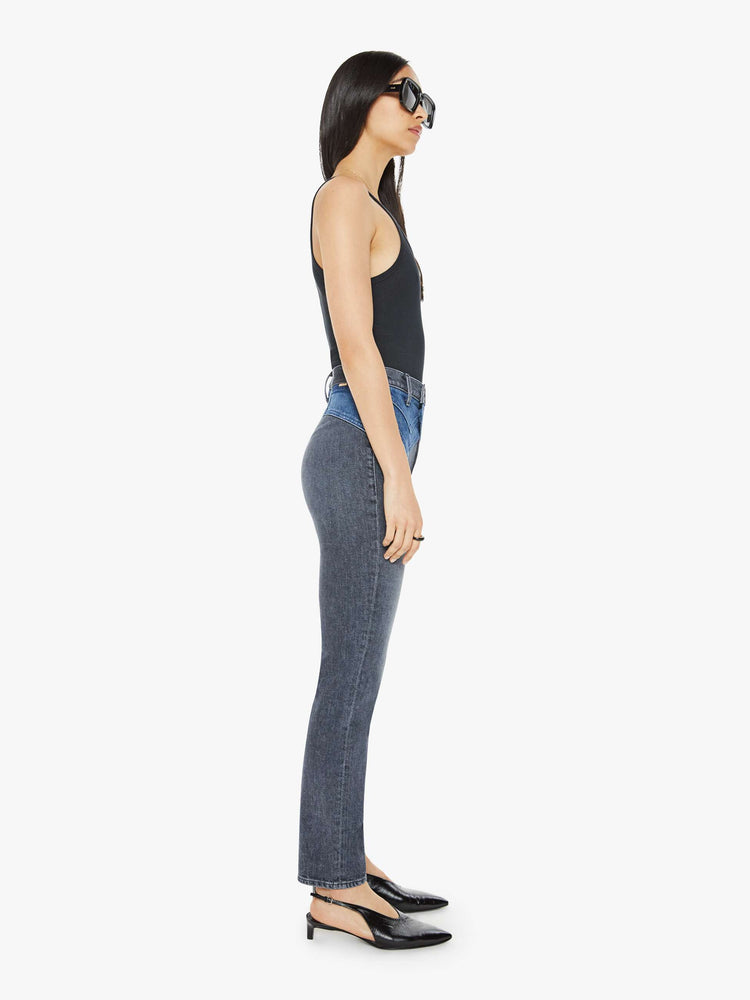 Side view of a woman in black and blue high-waisted jeans with a narrow straight leg, 2-button waistband, 30-inch inseam and a clean hem.