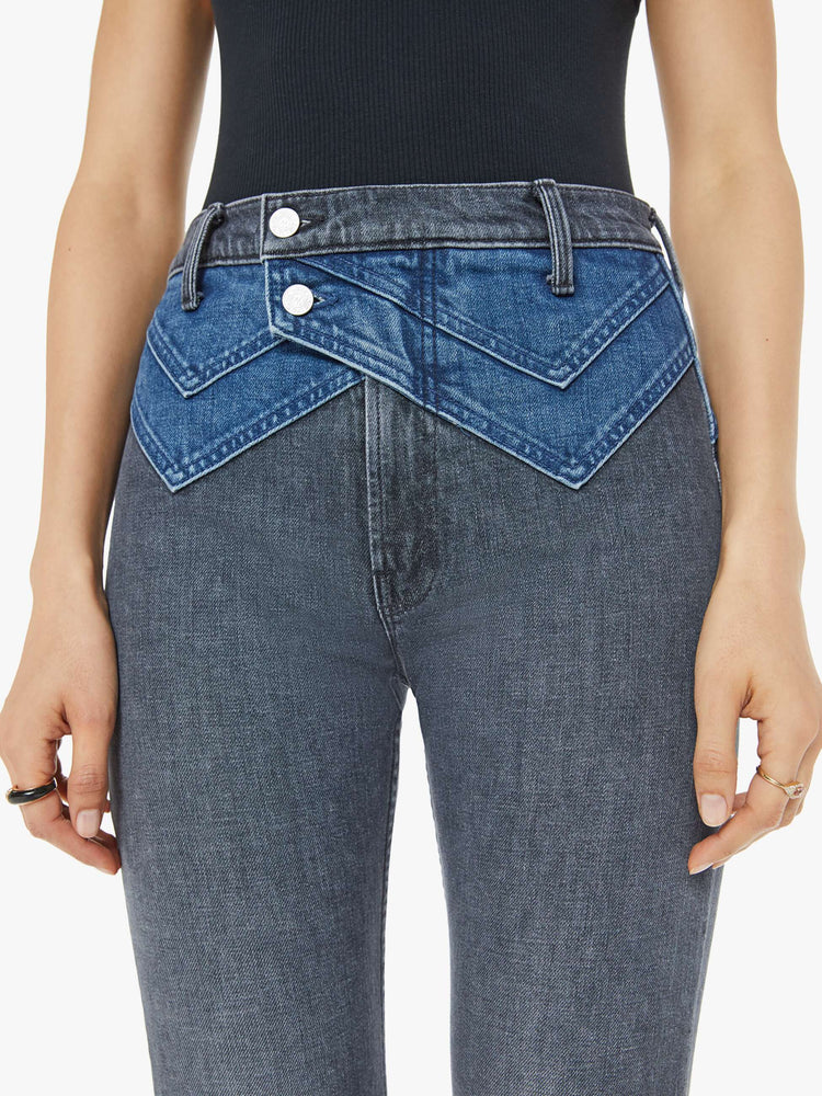 Close up waist view of a woman in black and blue high-waisted jeans with a narrow straight leg, 2-button waistband, 30-inch inseam and a clean hem.