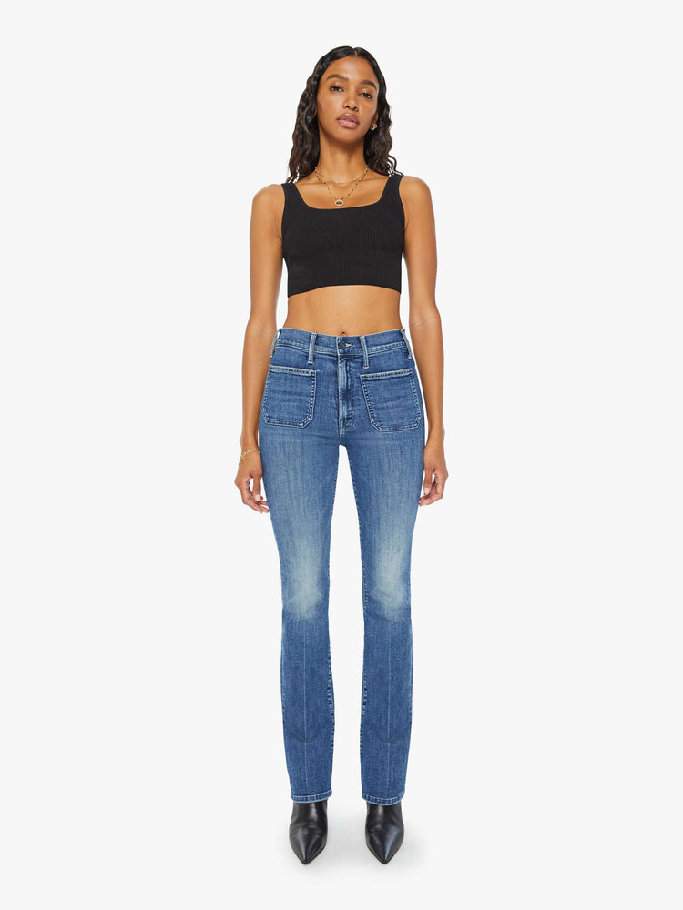 Front view of a woman high-rise bootcut is designed with front patch pockets, a long 32-inch inseam and a clean hem in a mid blue wash.