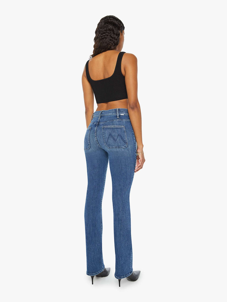 Back view of a woman high-rise bootcut is designed with front patch pockets, a long 32-inch inseam and a clean hem in a mid blue wash.