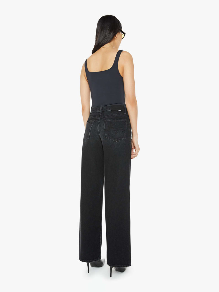 Back view of a woman in a black slouchy high-waisted jeans with a loose wide leg and a long 32-inch inseam with a clean hem.