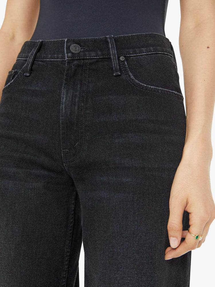 Close up view of a woman in a black slouchy high-waisted jeans with a loose wide leg and a long 32-inch inseam with a clean hem.