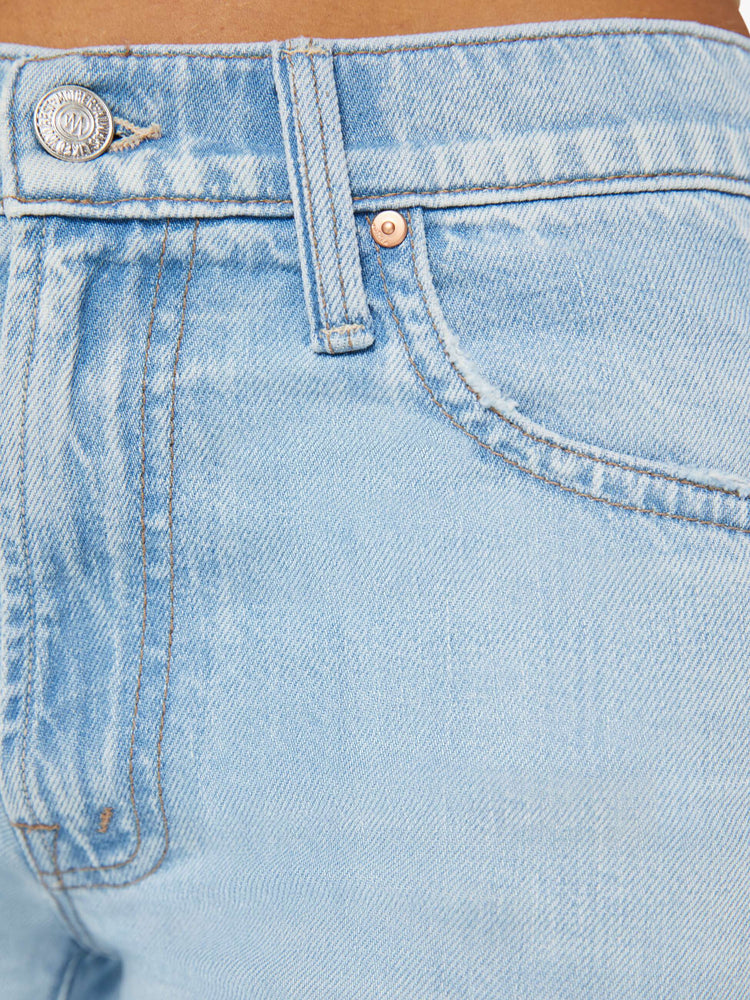 Detailed view of a woman in light blue mid-rise jeans with a wide straight leg, zip fly and clean 28.25-inch inseam.  