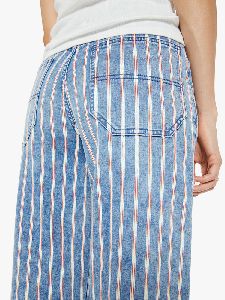 Close up view of a woman in a super high-waisted pants with a loose, straight leg, utility-inspired patch pockets, hammer loop and a long inseam in light blue with white stripes.