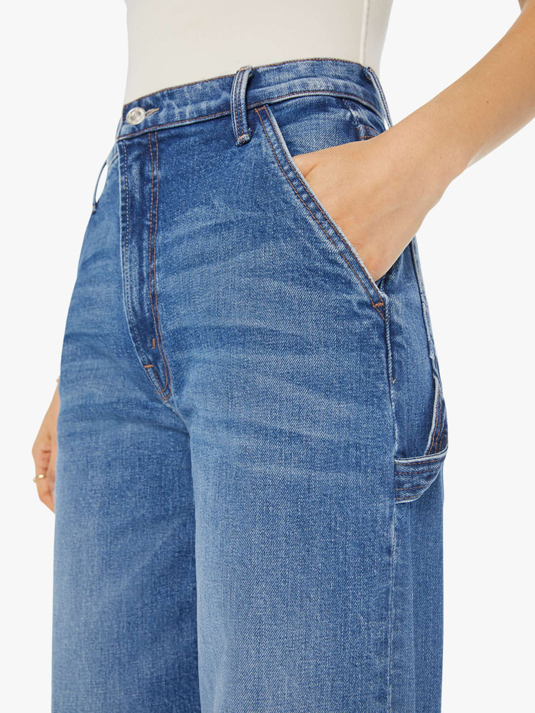 Close up view of a woman in a mid blue super high waisted jean with a loose, straight leg, utility-inspired patch pockets, a hammer loop.