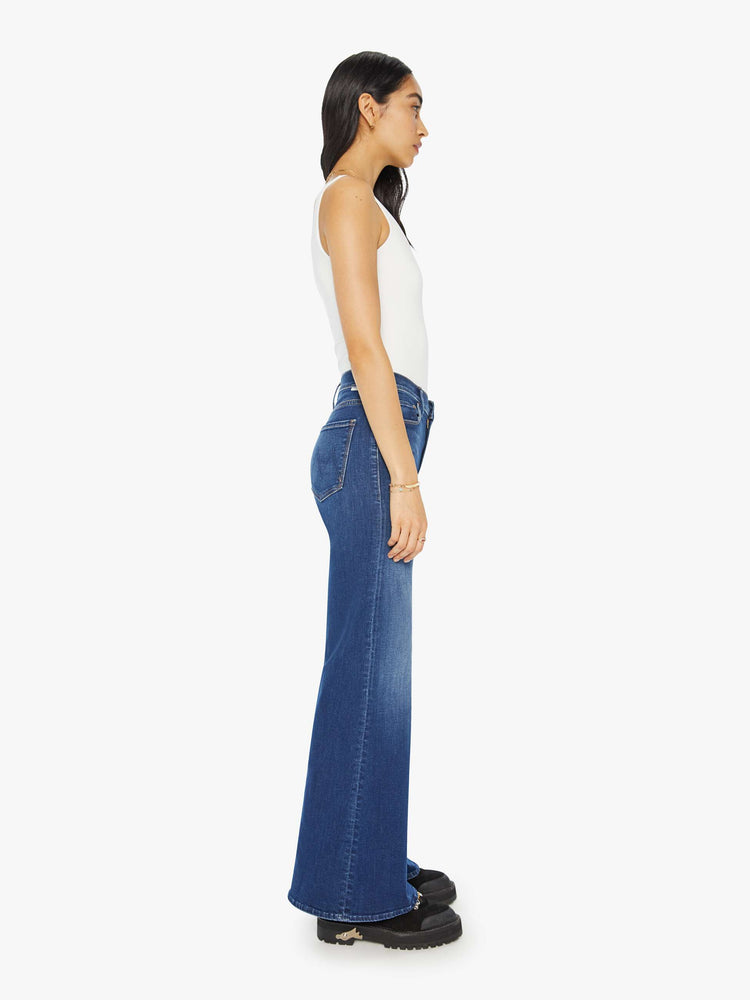 Side view of a woman flared, wide-leg jean with a high rise and a clean, 32-inch inseam in a mid blue wash.