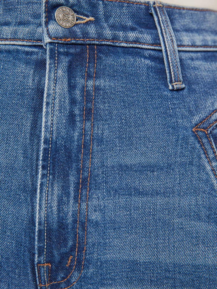 Swatch view of a woman in a mid blue high rise jean with a narrow straight leg, triangle pockets and a 31-inch inseam with a clean hem.