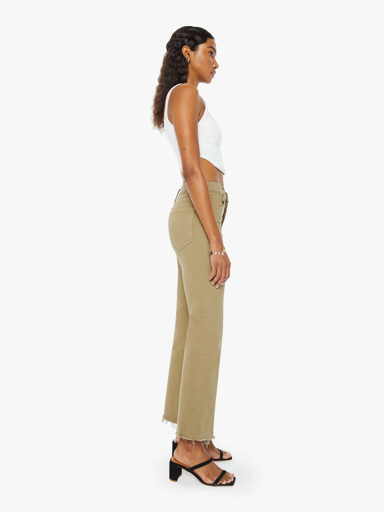 Side view of a woman in warm khaki high-rise flare with a button fly and a frayed hem.