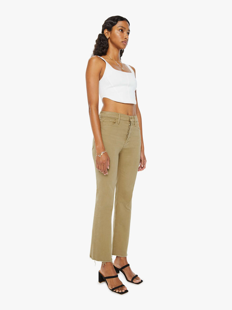 Angled view of a woman in warm khaki high-rise flare with a button fly and a frayed hem.