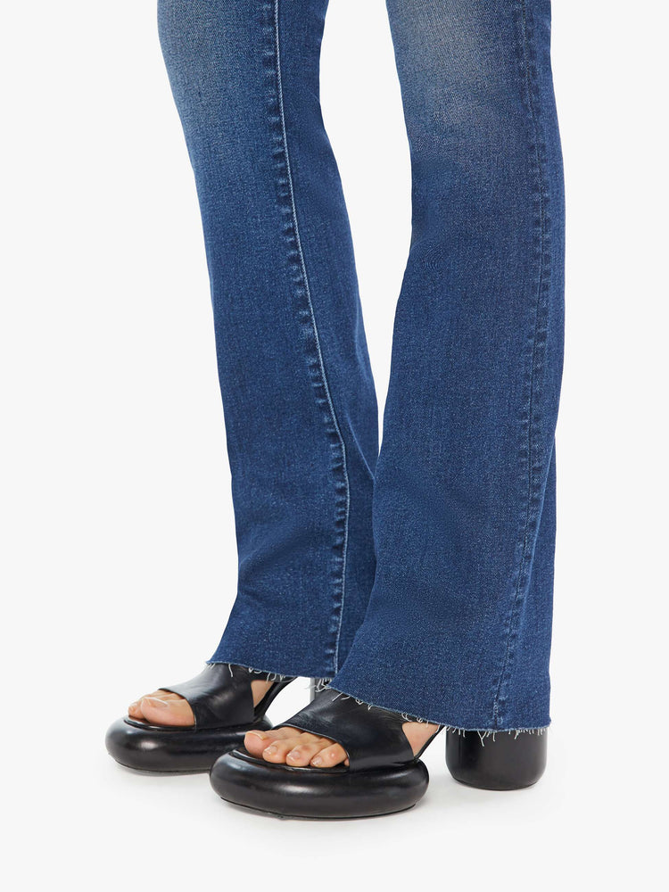 Hem view of a high waisted bootcut jean in a dark blue jean.