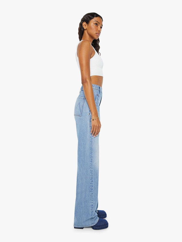 Side view of a woman wide-leg jeans with a super high rise, patch pockets and a long 34-inch inseam with a clean hem in a light blue wash.