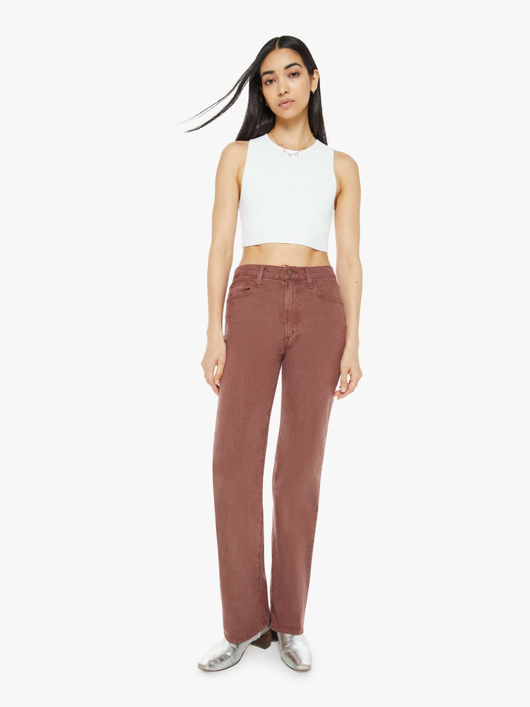 Front view of a woman in a brown high-waisted pants with a wide straight leg, zip fly and a long 32-inch inseam with a clean hem.