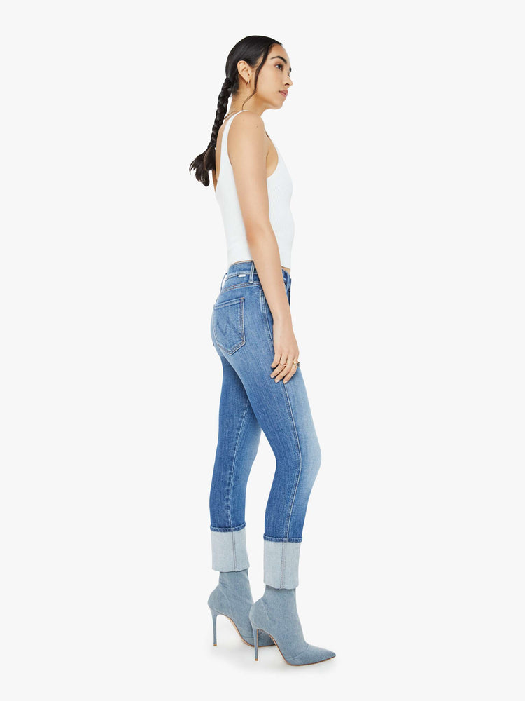 Side view of a woman in a mid blue high-rise straight-leg jeans with an ankle-length inseam and a clean, cuffed hem.