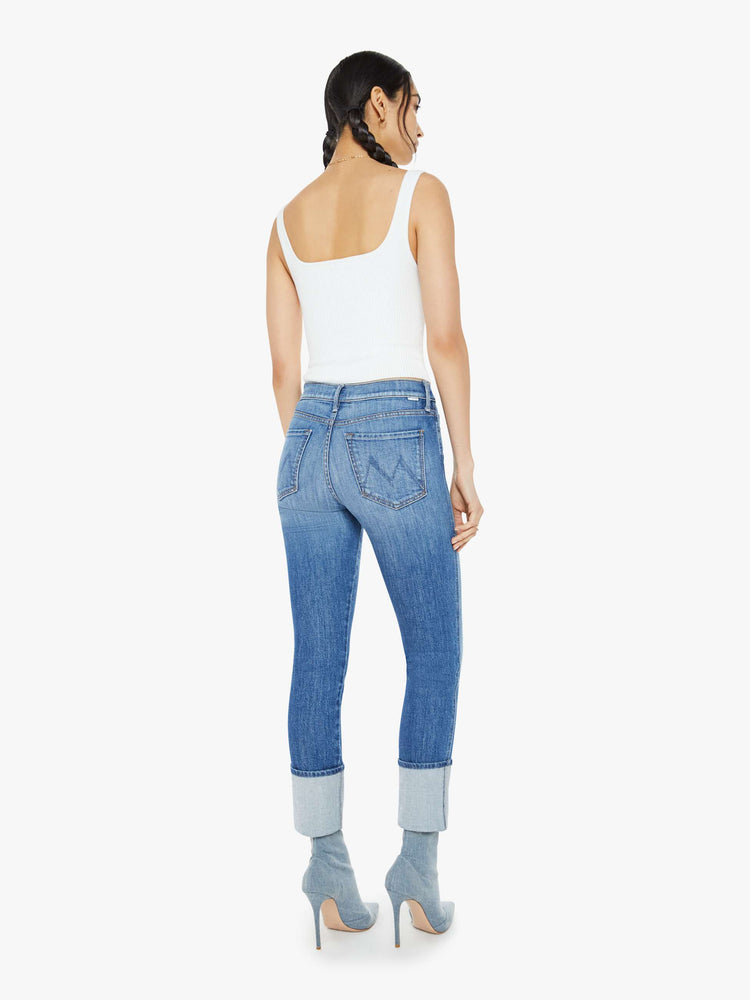 Back view of a woman in a mid blue high-rise straight-leg jeans with an ankle-length inseam and a clean, cuffed hem.