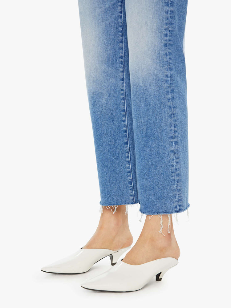 Swatch view of a woman in light blue mid-rise jeans with a wide straight leg, zip fly, an ankle-length inseam and a frayed hem.