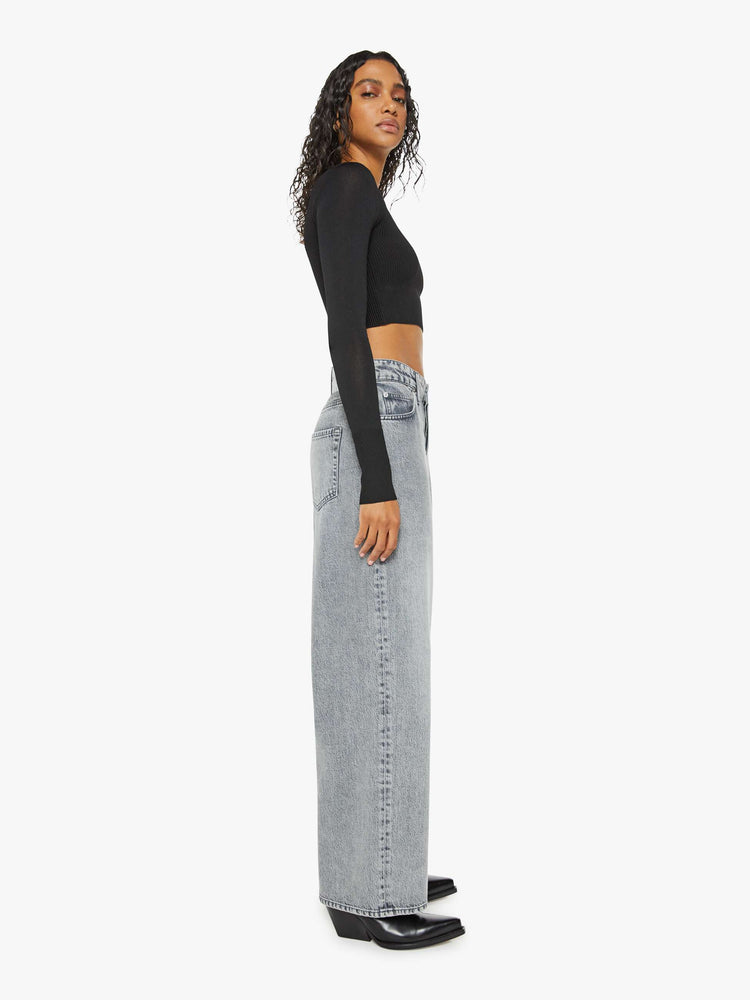 Side view of a woman in a grey wide leg super high-waisted jeans have a 29-inch inseam and a loose, slightly baggy fit.