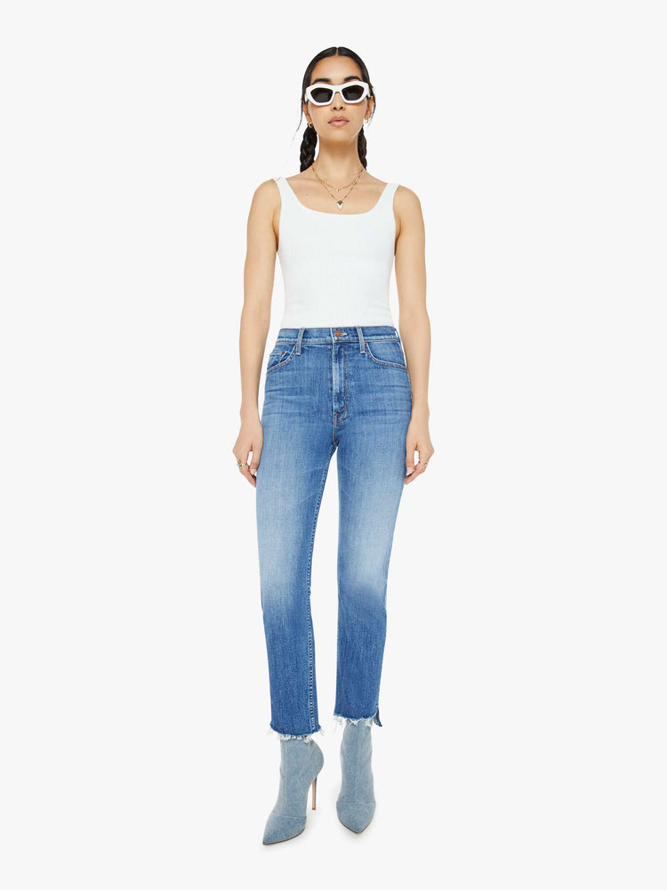 Front view of a mid blue high-rise straight-leg jeans with an ankle-length inseam and a frayed step-hem.