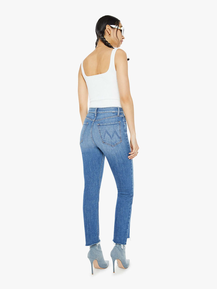 Back view of a mid blue high-rise straight-leg jeans with an ankle-length inseam and a frayed step-hem.