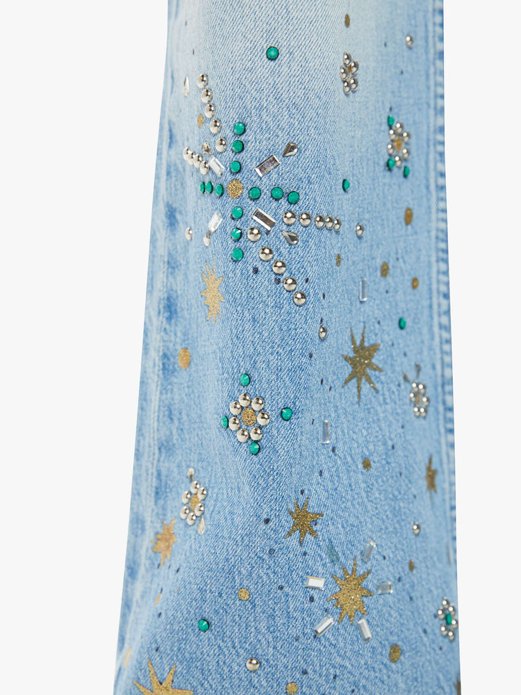 Swatch view of a woman in a light blue high rise bootcut jean embellished with paint, glitter and studs.