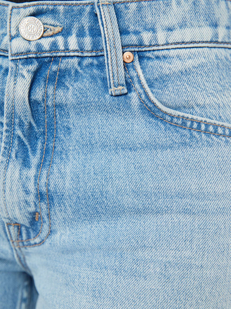 Waist swatch view of a woman in a light blue high rise bootcut jean embellished with paint, glitter and studs.