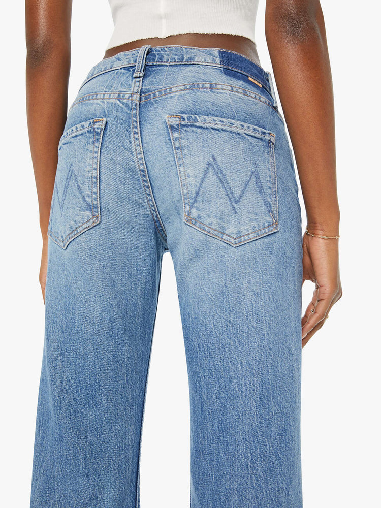 Detailed view of a woman in light blue mid-rise bootcut designed for a looser fit through the leg while fitted throughout the waist and hips. 