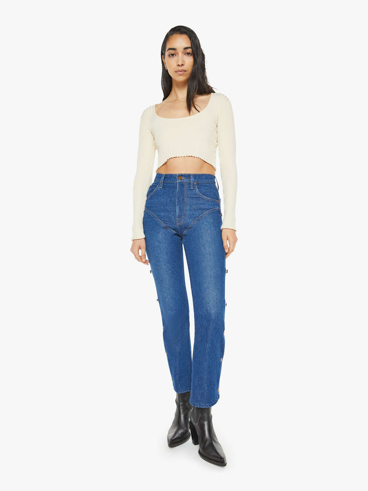 Front view of a woman in a high rise straight leg jean with chaps inspired buttons down each side with a 29 inch inseam in a classic blue.