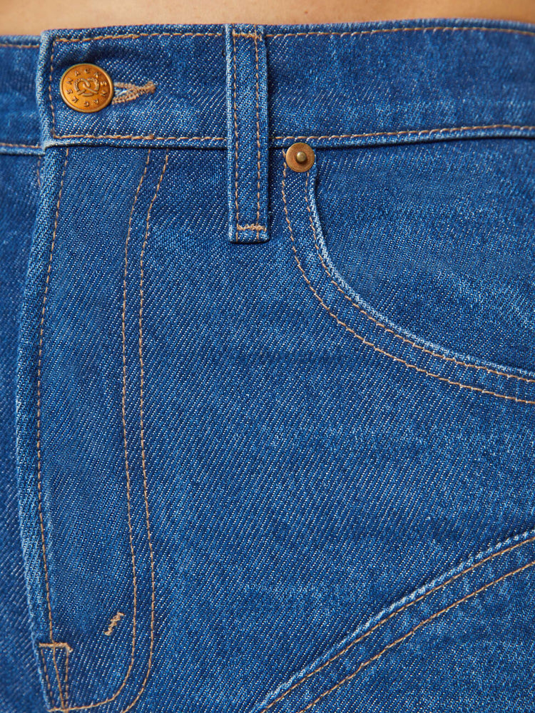 Swatch view of a woman in a high rise straight leg jean with chaps inspired buttons down each side with a 29 inch inseam in a classic blue.