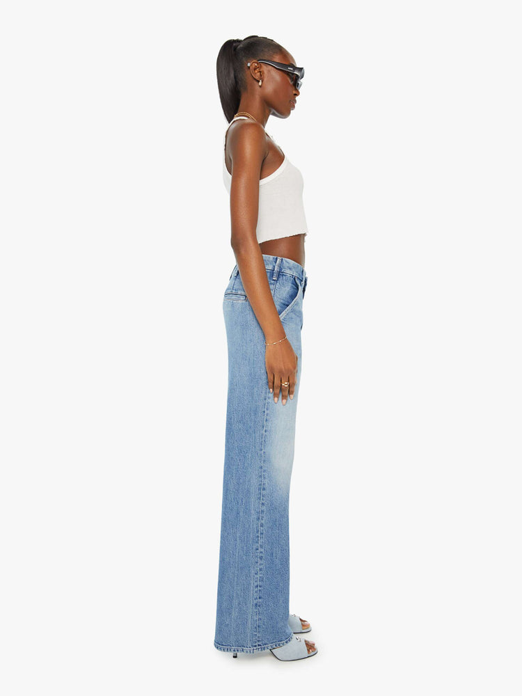 Side view of a woman in light blue high rise jeans that sit lower with slit pockets and a clean hem. 