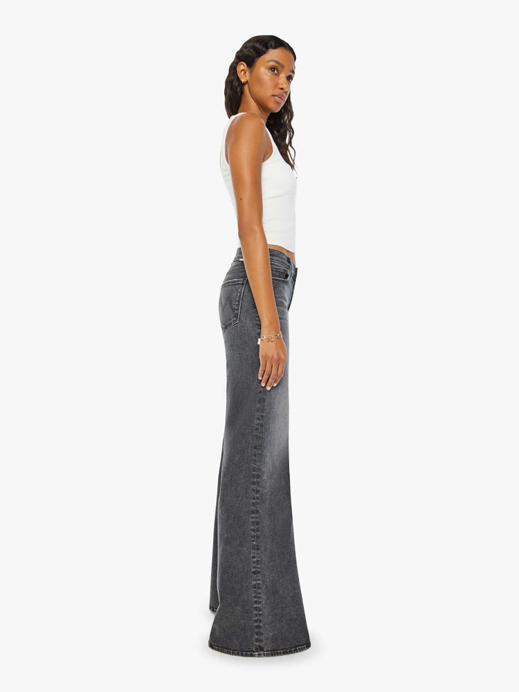 Side view of a woman dark grey flared, wide-leg jean with a mid rise and a clean, 34-inch inseam.