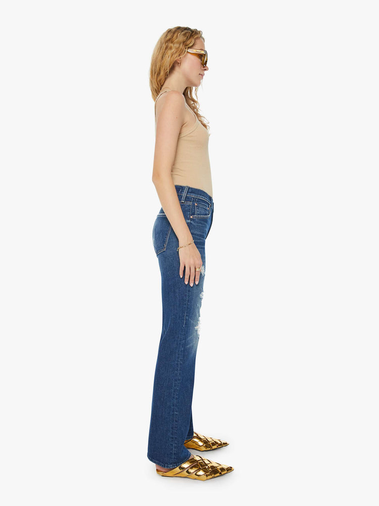 Side view of a woman in dark blue high-waisted jeans designed to sit lower on the waist with a wide bootcut and a long 32-inch inseam. 