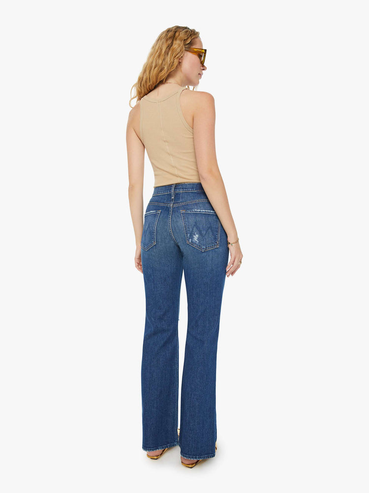 Back view of a woman in dark blue high-waisted jeans designed to sit lower on the waist with a wide bootcut and a long 32-inch inseam. 