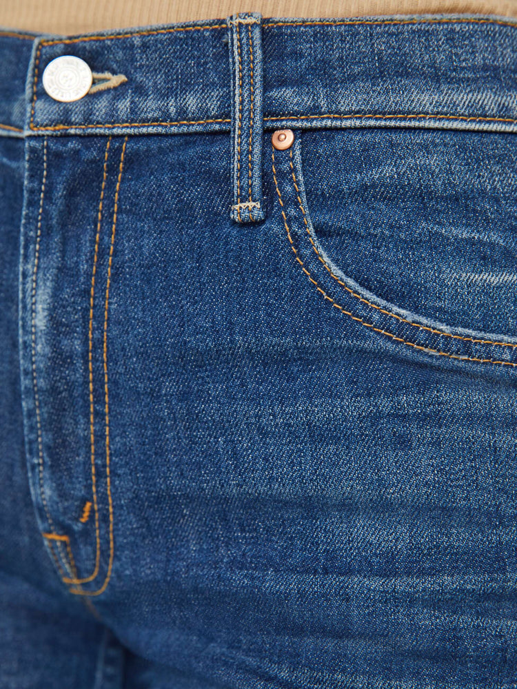 Detailed view of a woman in dark blue high-waisted jeans designed to sit lower on the waist with a wide bootcut and a long 32-inch inseam. 