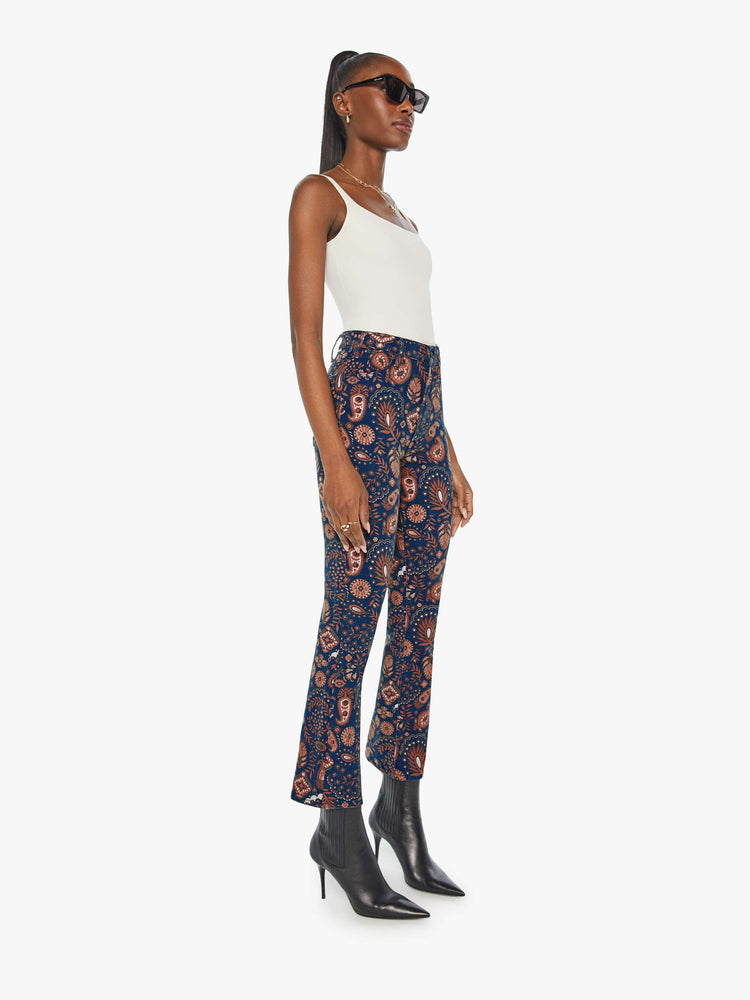 Side angle view of a woman in a navy pink paisley high-waisted bootcut with a 28.25-inch inseam and a clean hem.