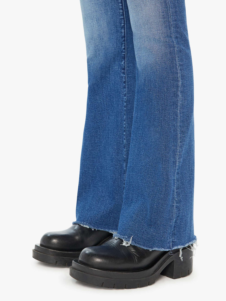 Swatch view of a woman in mid-blue md-rise jeans with a flared leg, long 32-inch inseam and a frayed hem.