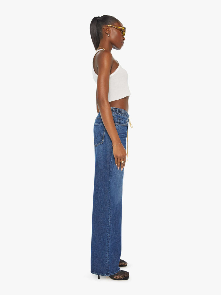 Side view of a woman in a dark blue wide-leg jean with a relaxed fit that's designed to sit on the hips with an elastic drawstring waistband, 32-inch inseam and a clean hem. 